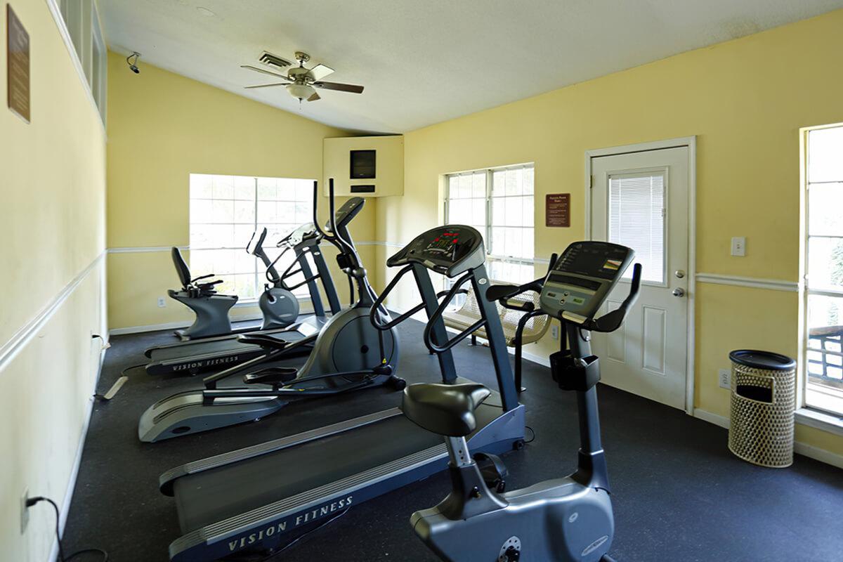 Fitness room with exercise equipment and windows.